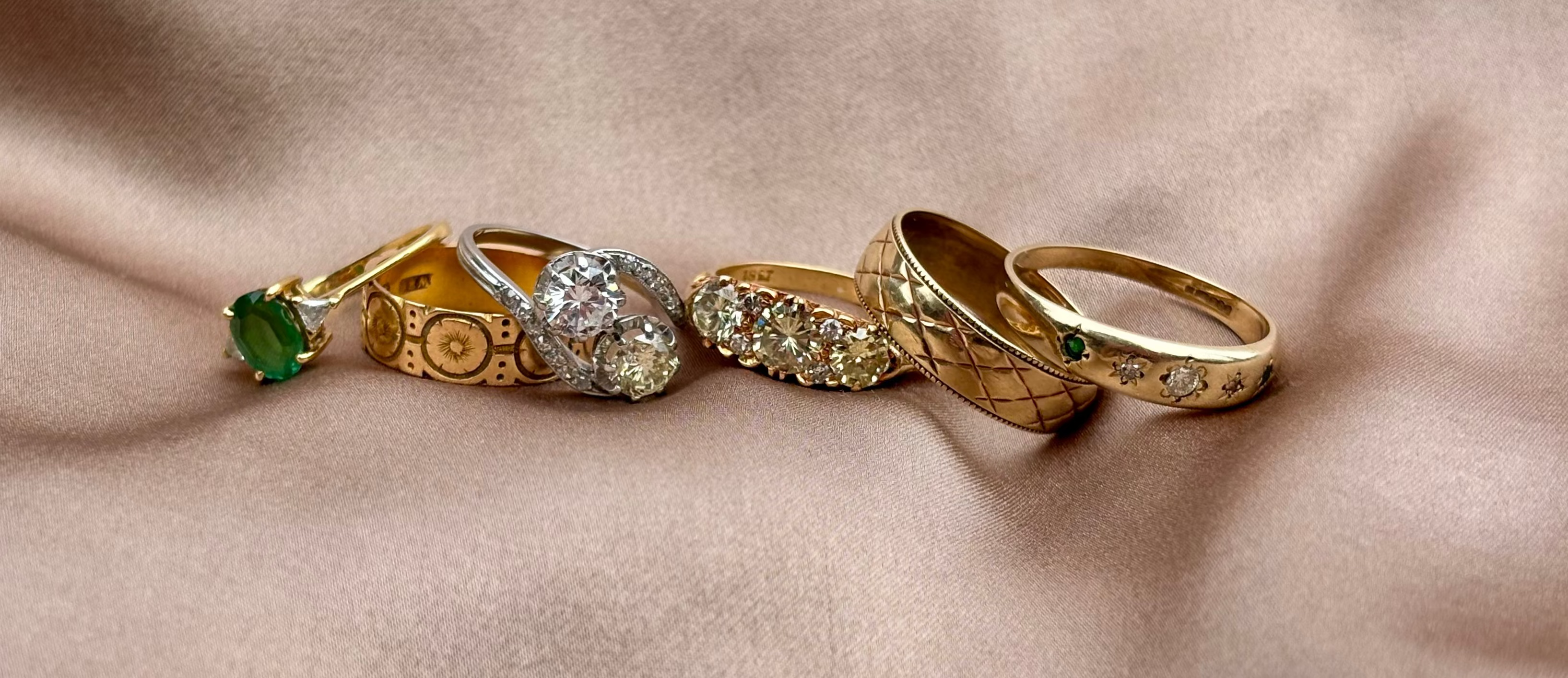 Set of gold rings with gemstones on a beige fabric background