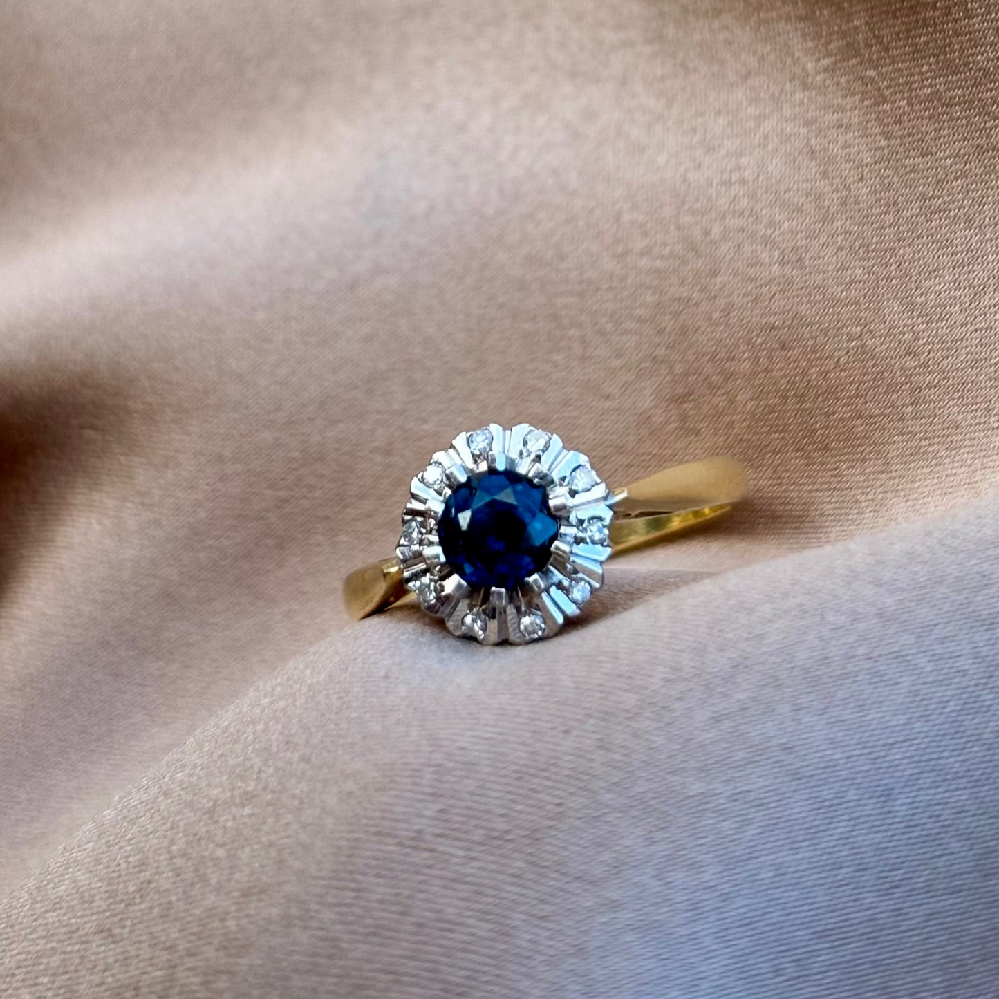 Gold ring with a blue gemstone on a beige fabric background
