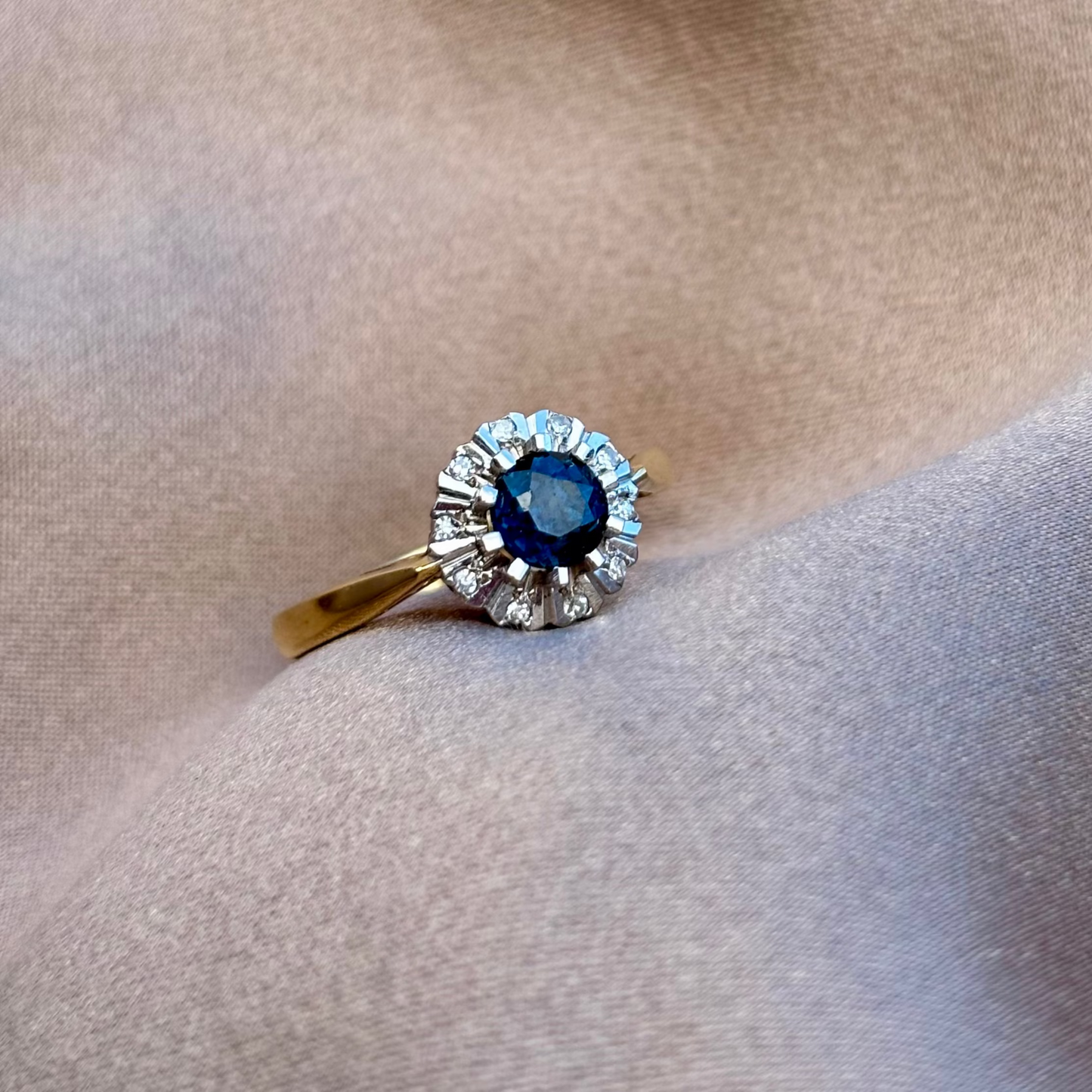 Gold ring with a blue gemstone on beige fabric