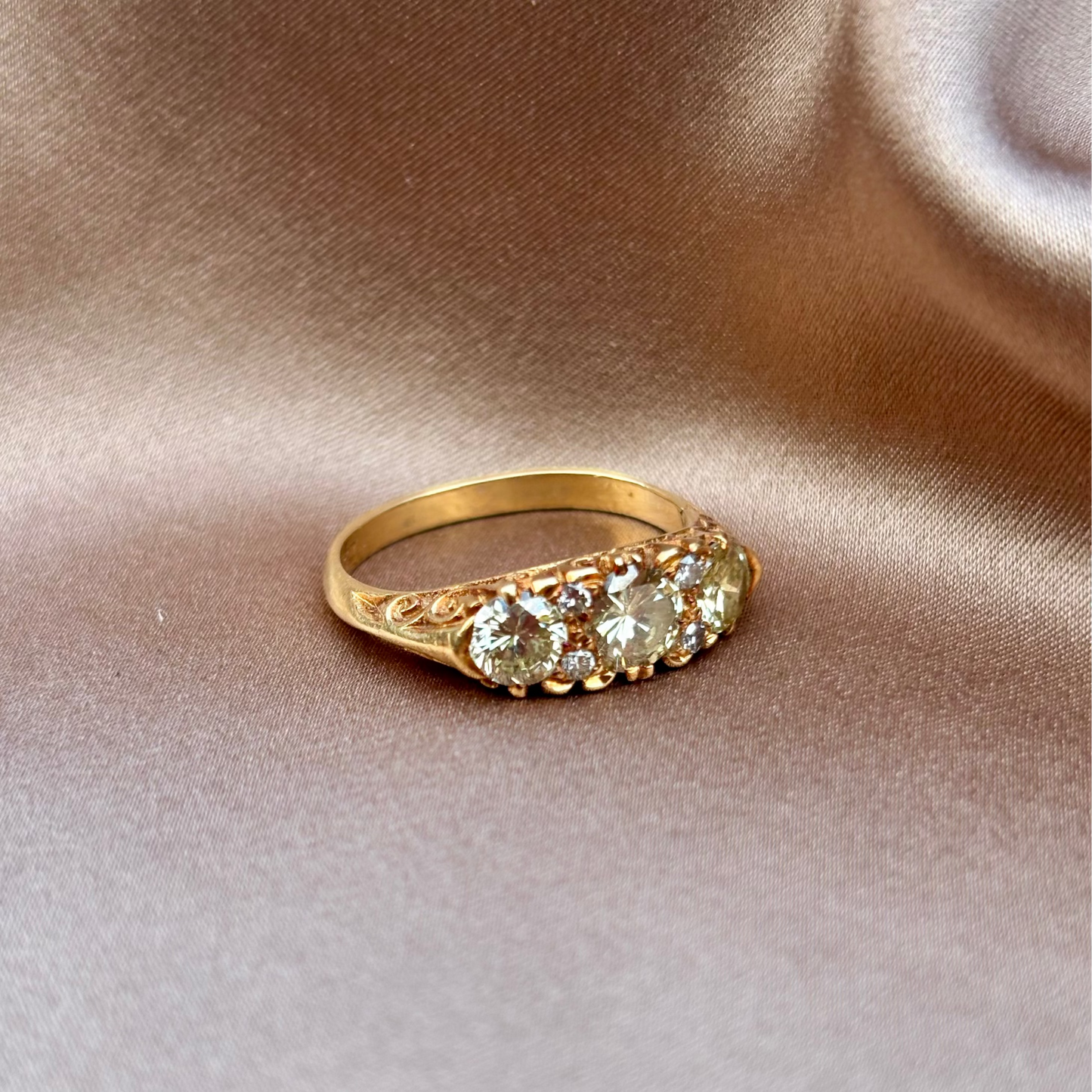 Gold engagement ring with three diamonds on a beige fabric background