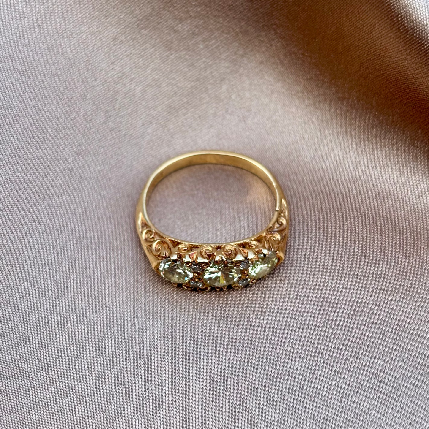 Gold engagement ring with champagne diamonds engraved setting on a beige fabric background