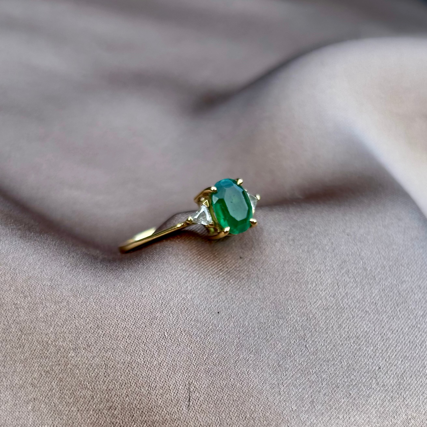 Gold ring with a green gemstone on beige fabric