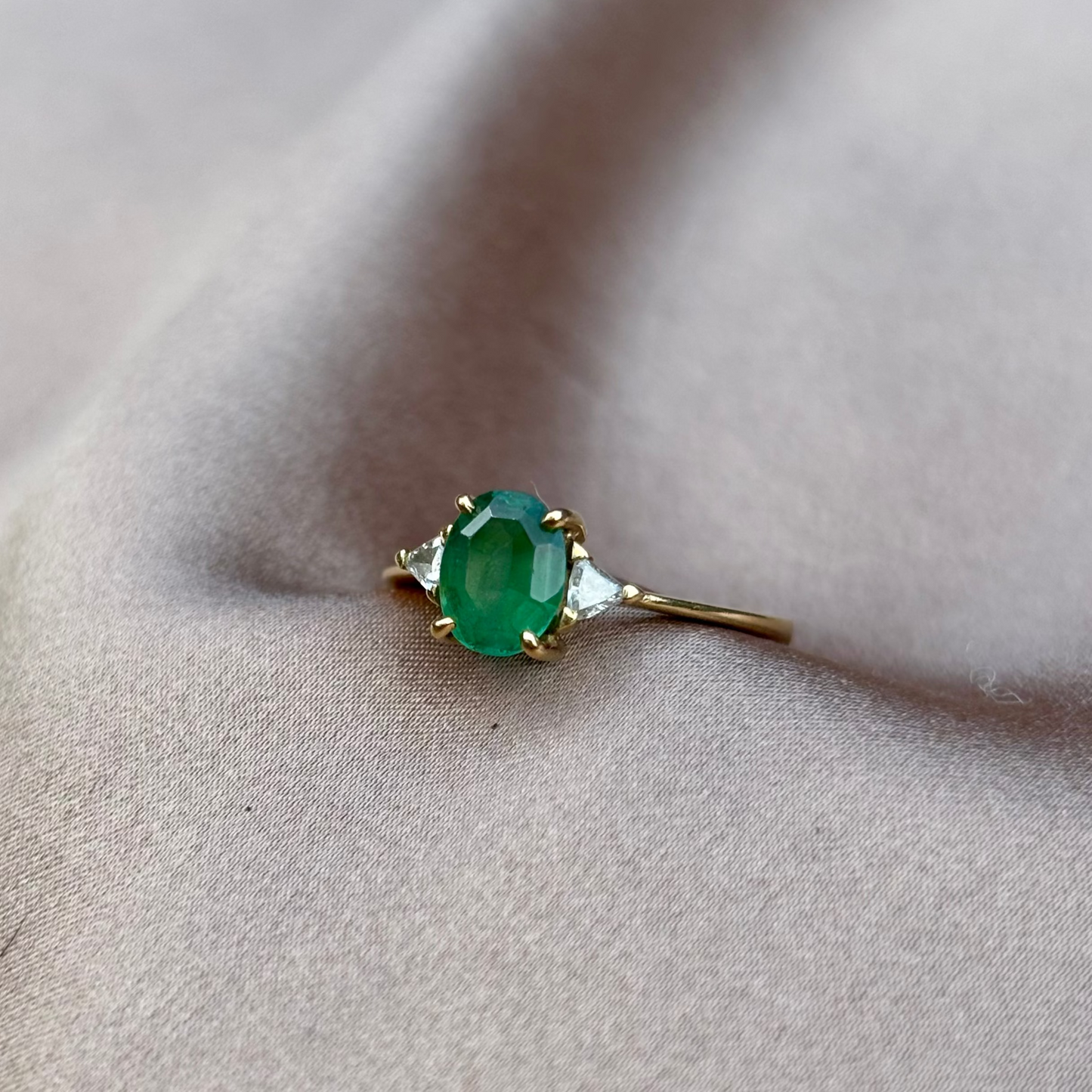 Gold ring with a green gemstone on a beige fabric background