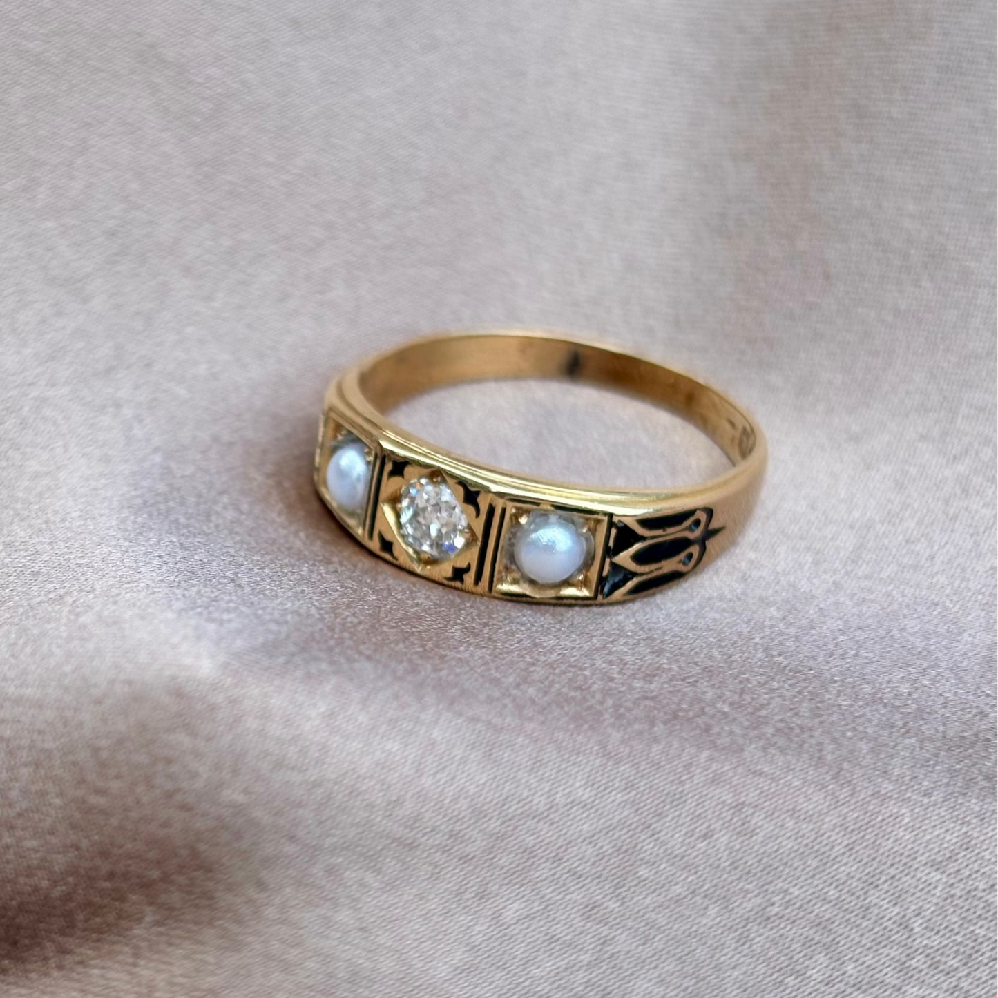 Gold ring with embedded stones on a beige fabric background