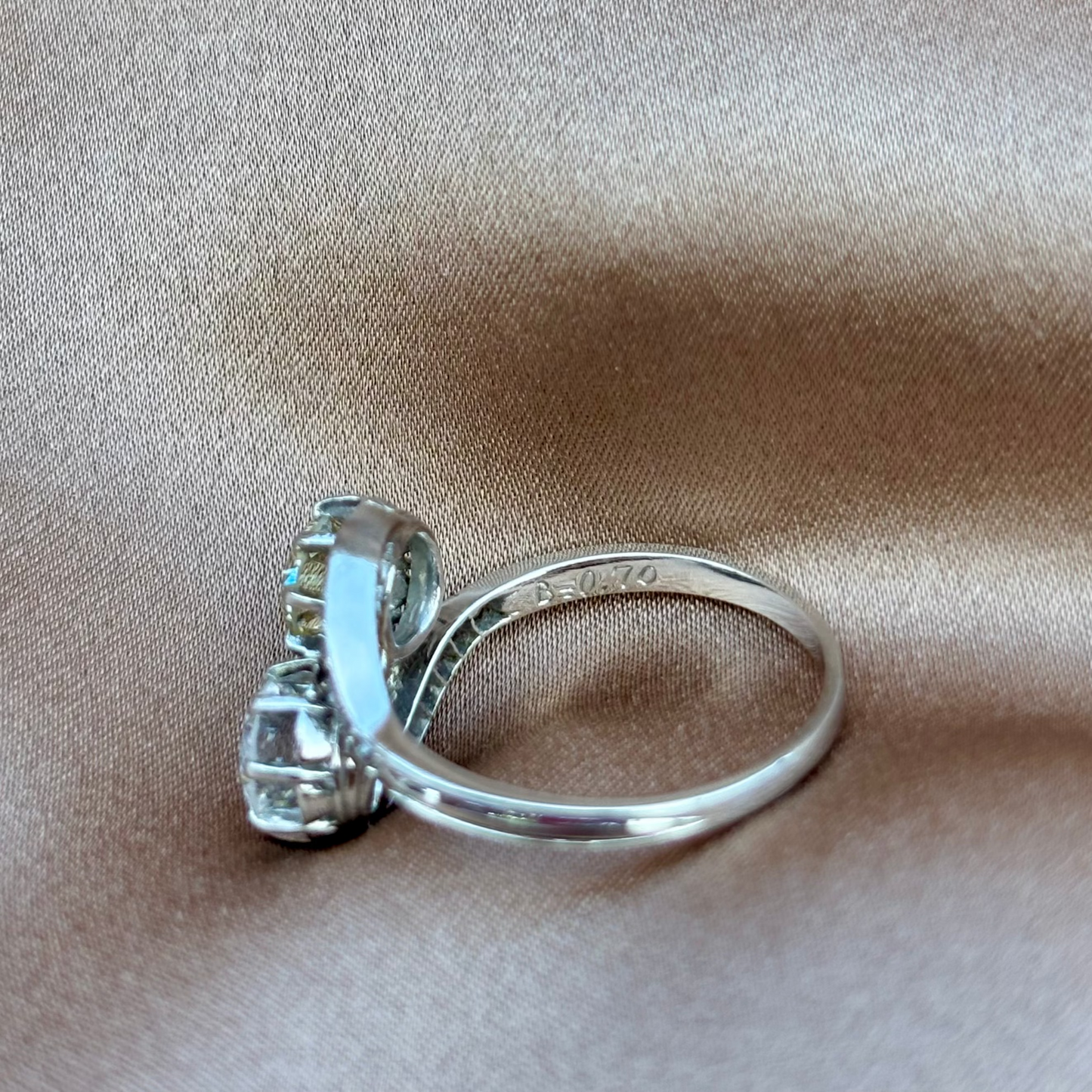 platinum ring with a diamond on a beige fabric background
