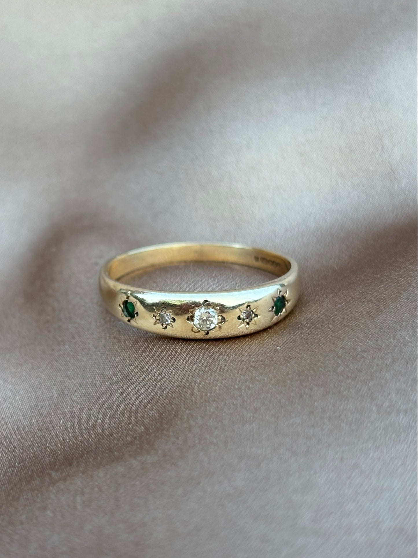 Gold ring with embedded stones on a soft beige fabric background