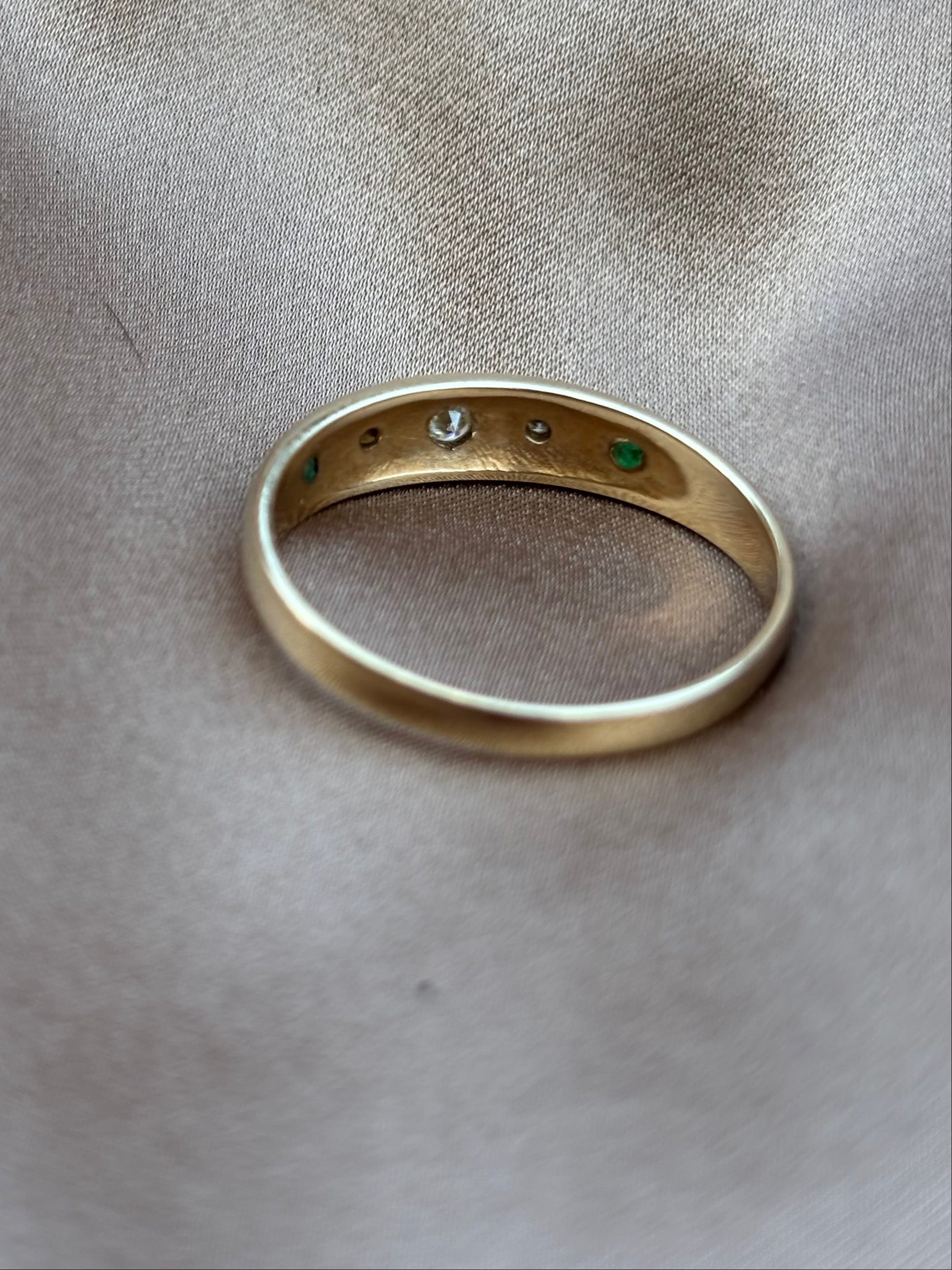 Gold ring with embedded stones on a beige fabric background