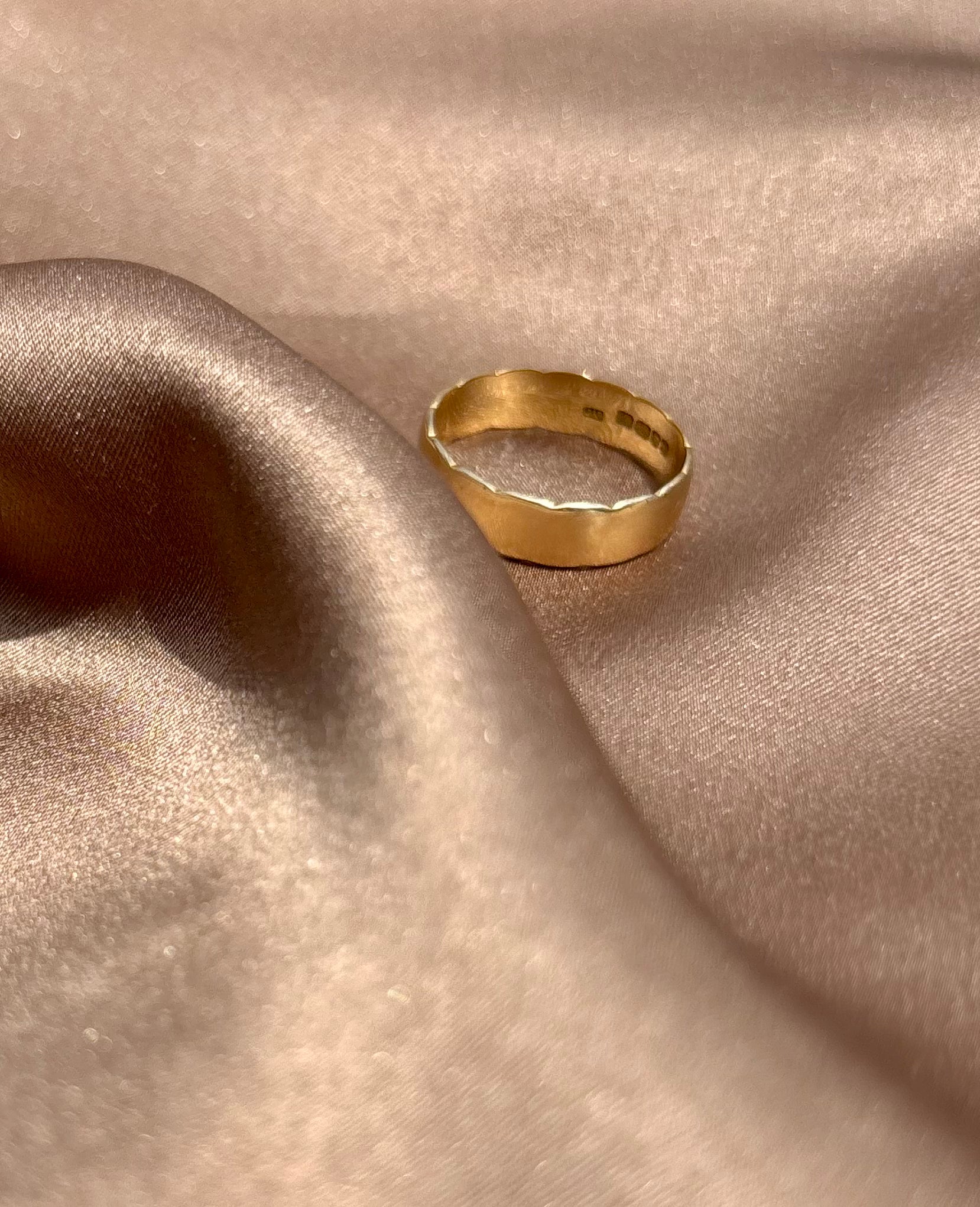 Gold ring on a textured beige fabric surface