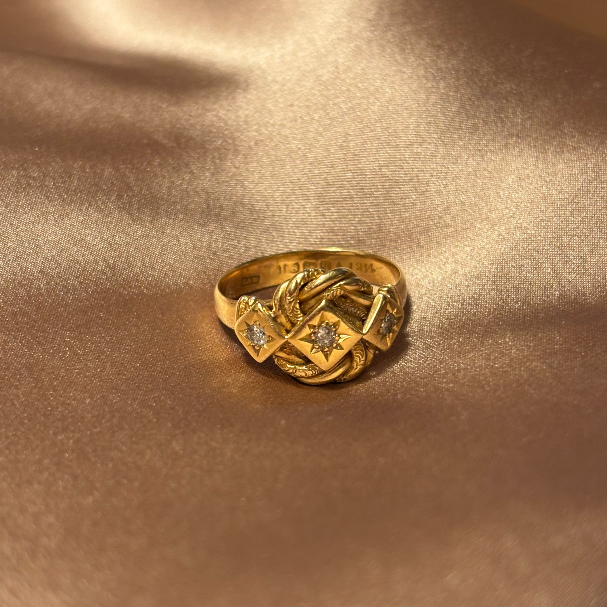 Gold ring with intricate design on a beige fabric background