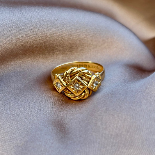 Gold ring with diamond accents on a soft fabric background