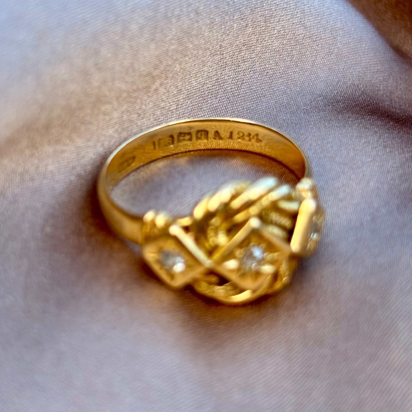 Gold ring with intricate design on a soft fabric background