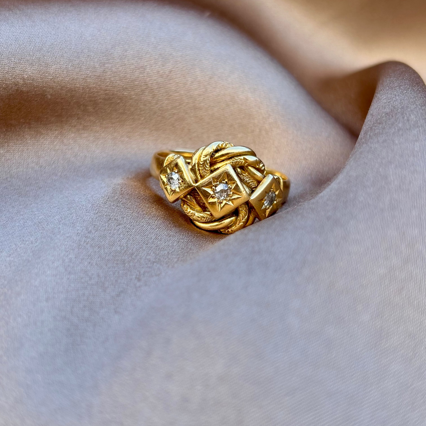 Gold ring with diamond accents on a beige fabric background