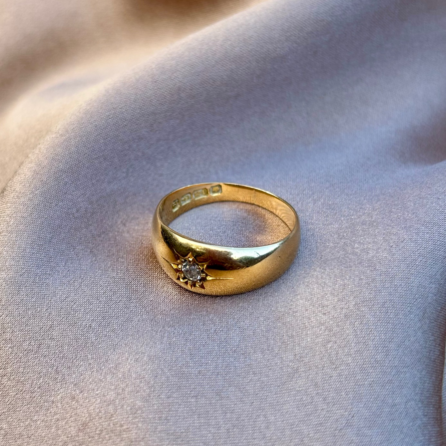 Gold ring with a diamond on a soft fabric background