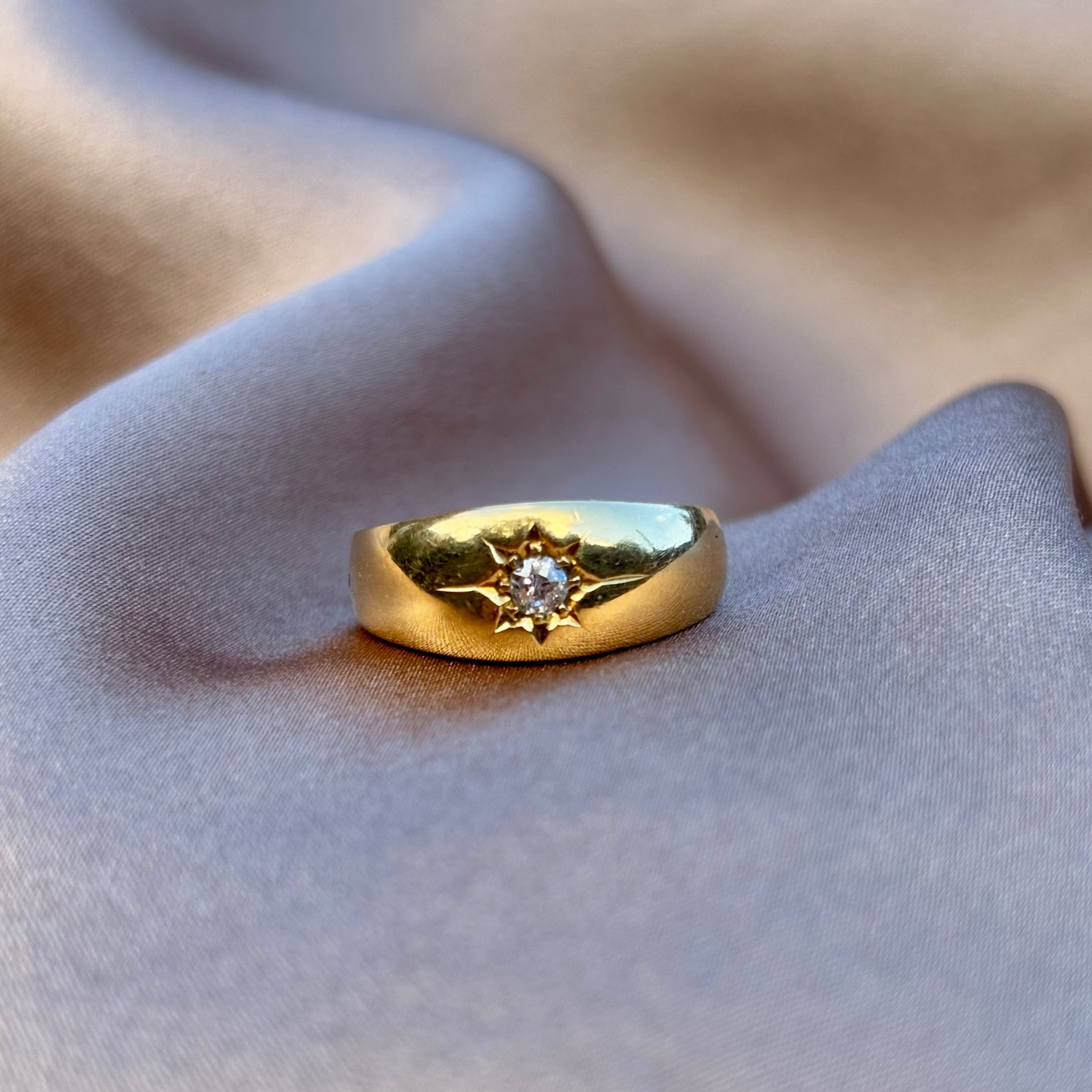 Gold ring with a diamond on a soft fabric background