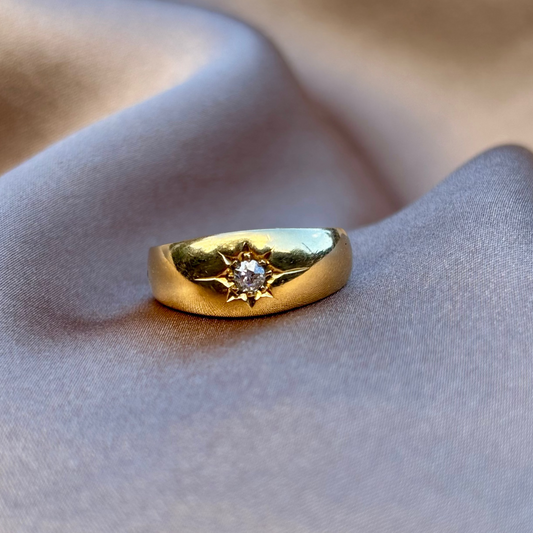 Gold ring with a diamond on a soft fabric background