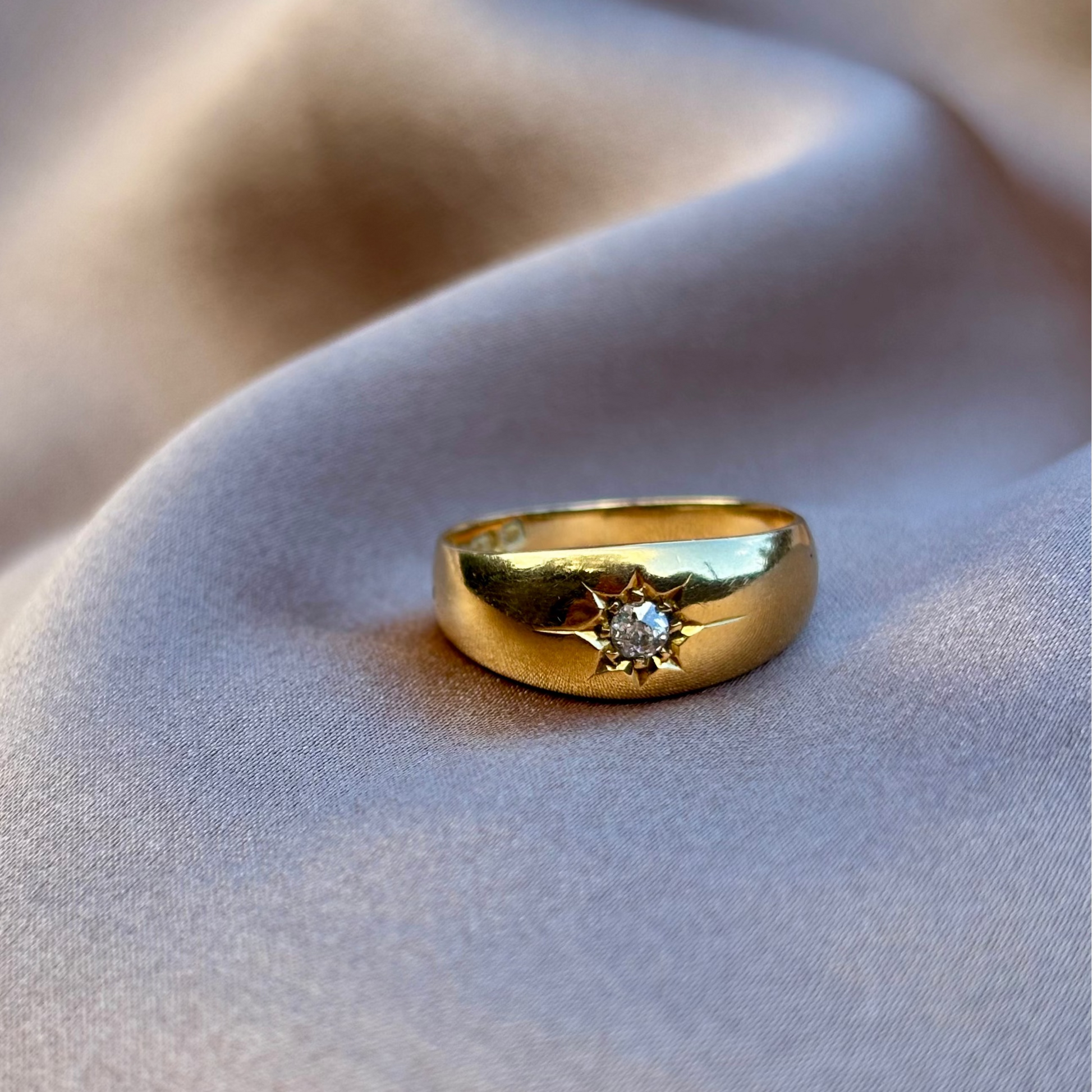 Gold ring with a diamond on a soft fabric background