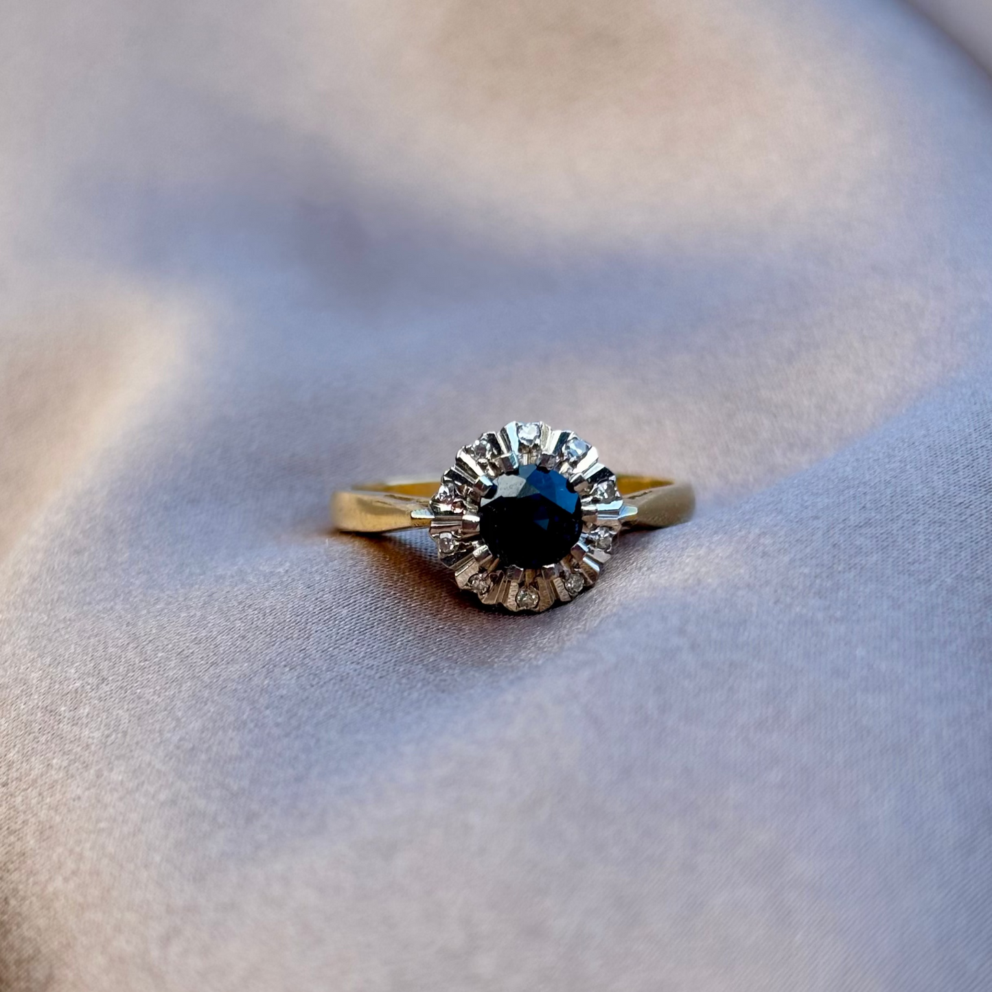 Gold ring with a blue gemstone on a beige fabric background