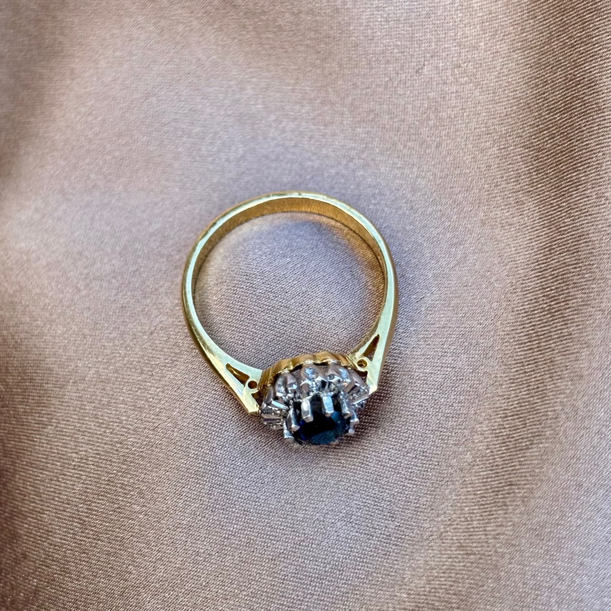 Gold ring with a dark gemstone on a beige fabric background