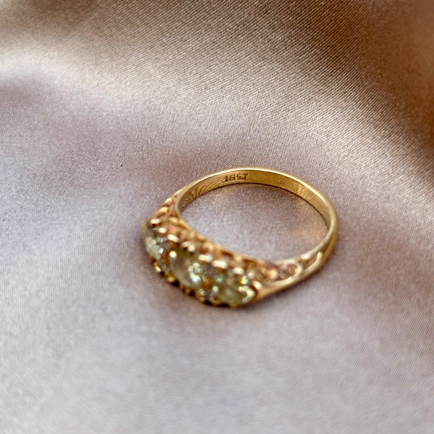 Gold engagement ring with champagne diamonds engraved setting on a beige fabric background