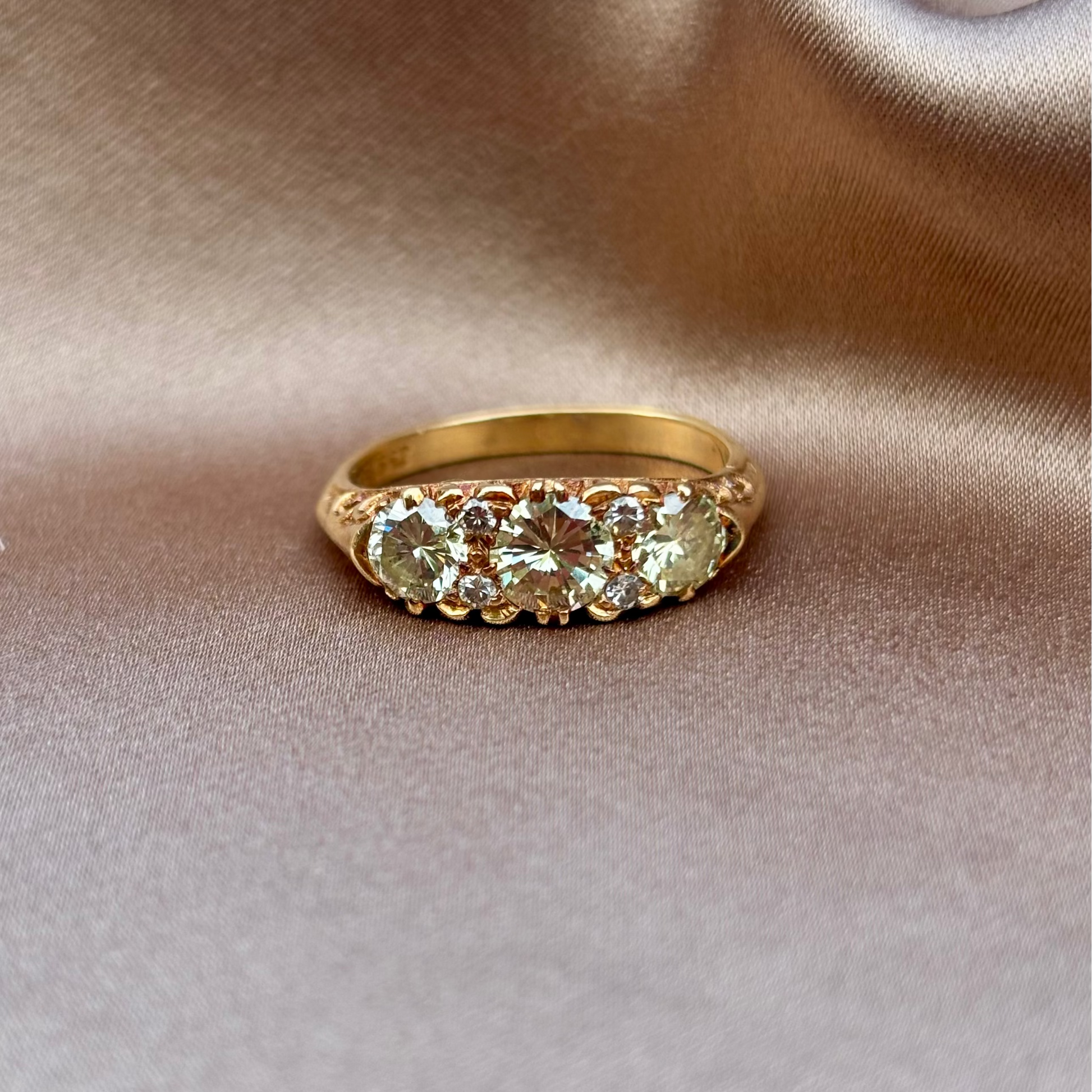 Gold ring with gemstones on a beige fabric background
