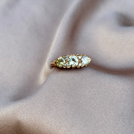 Gold engagement ring with champagne diamonds engraved setting on a beige fabric background