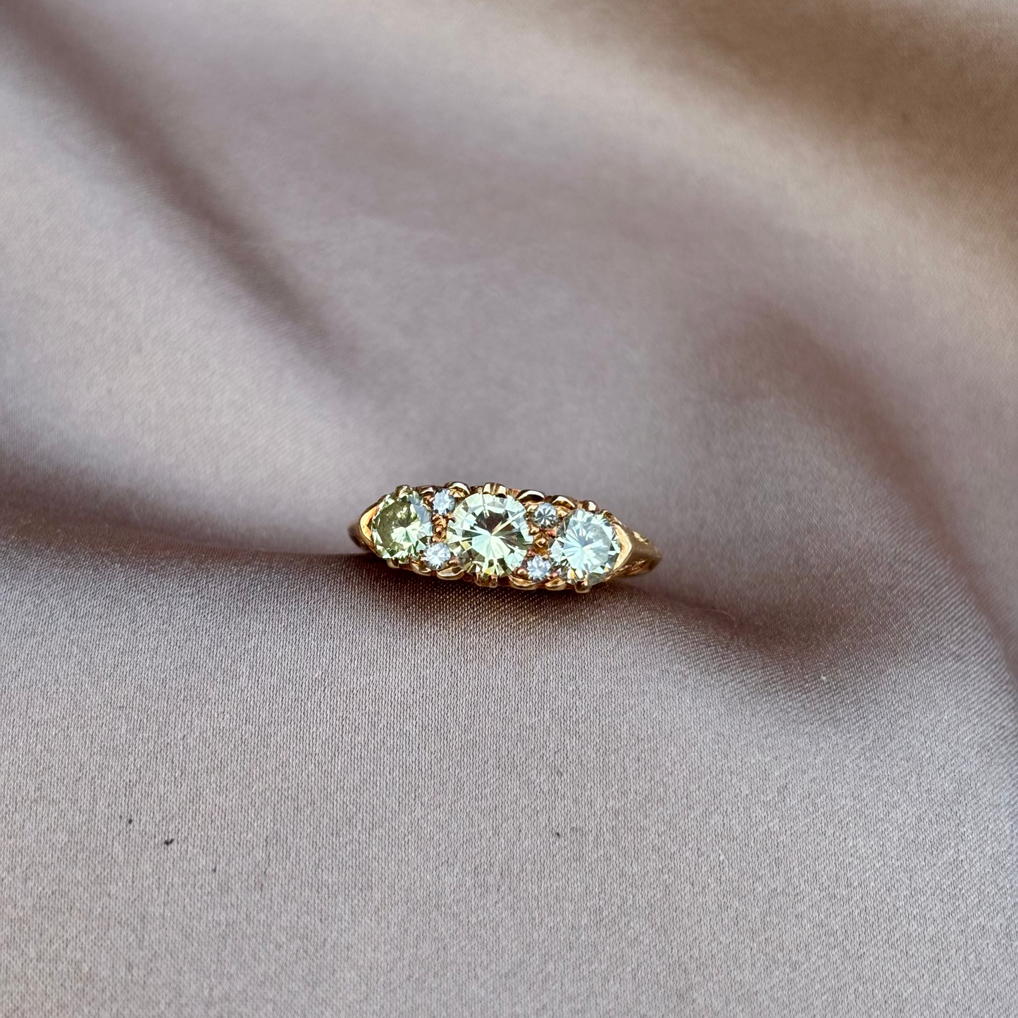 Gold engagement ring with champagne diamonds engraved setting on a beige fabric background