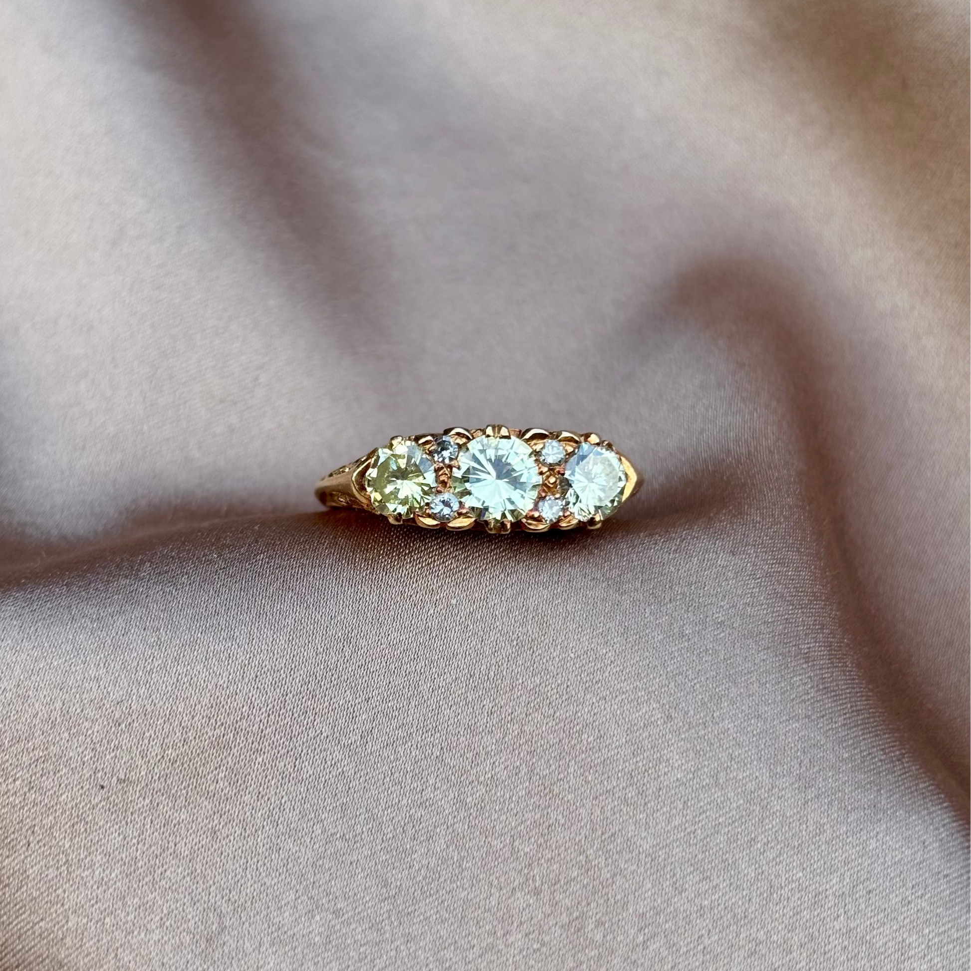 Gold engagement ring with champagne diamonds engraved setting on a beige fabric background