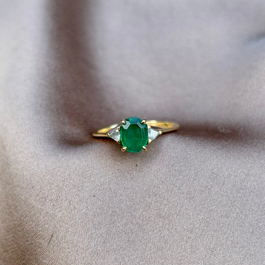 Gold ring with a green gemstone on a beige fabric background