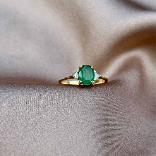 Gold ring with a green gemstone on beige fabric