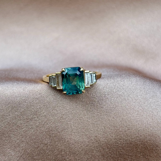 Gold ring with a green gemstone on a beige fabric background