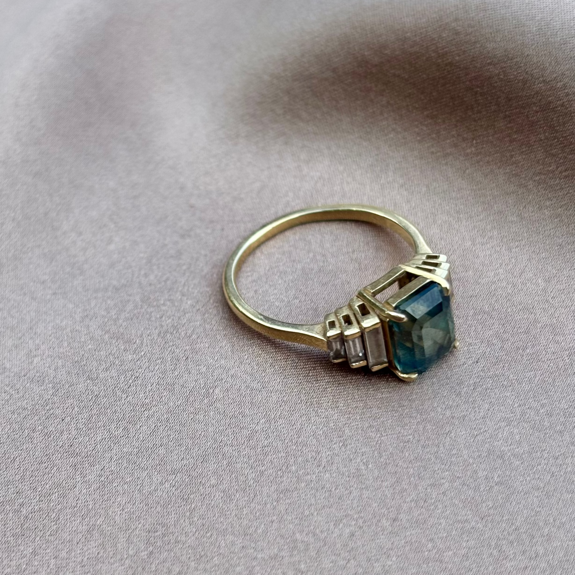 Gold ring with a blue gemstone on a beige fabric background