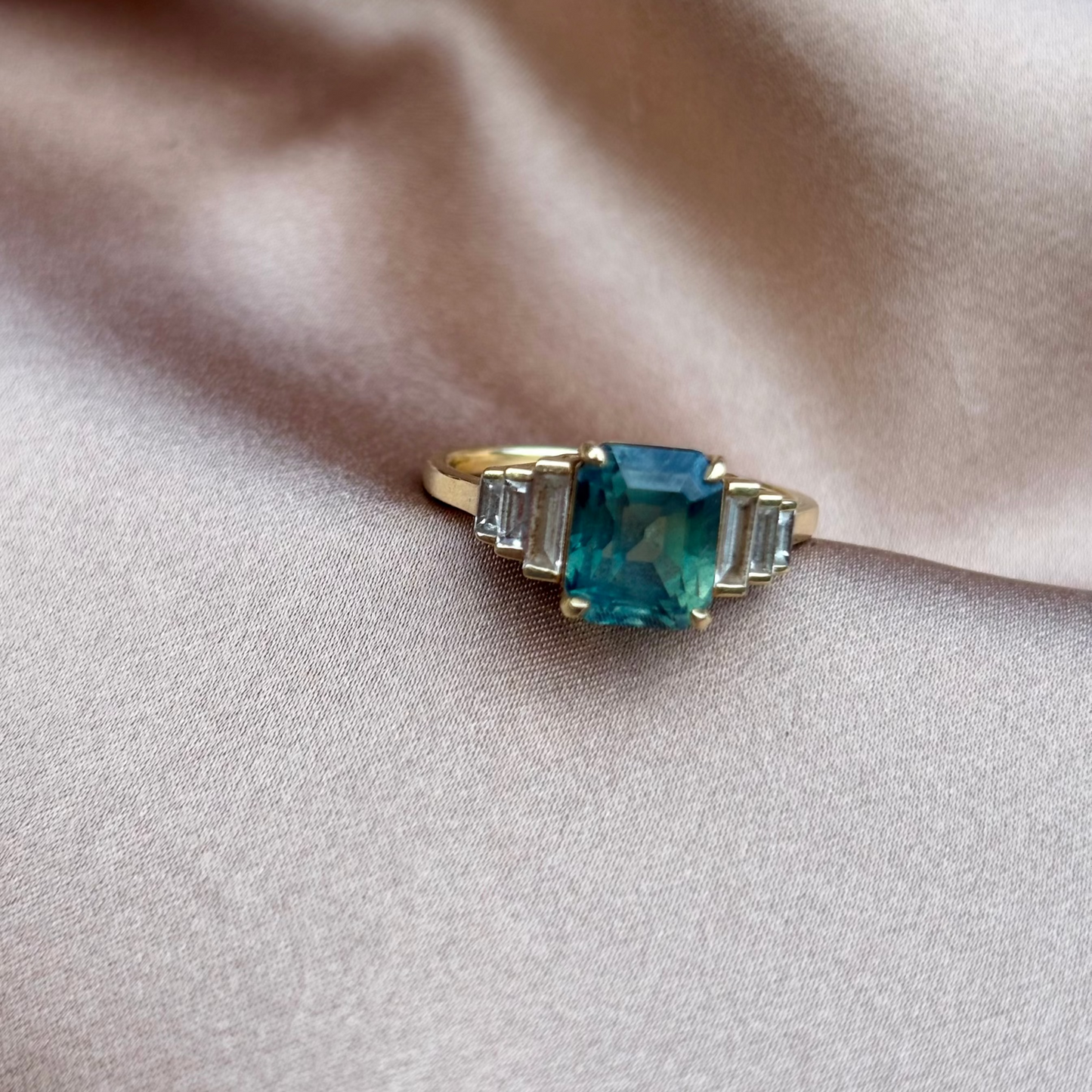 Gold ring with a blue gemstone on beige fabric