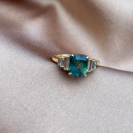 Gold ring with a blue gemstone on beige fabric