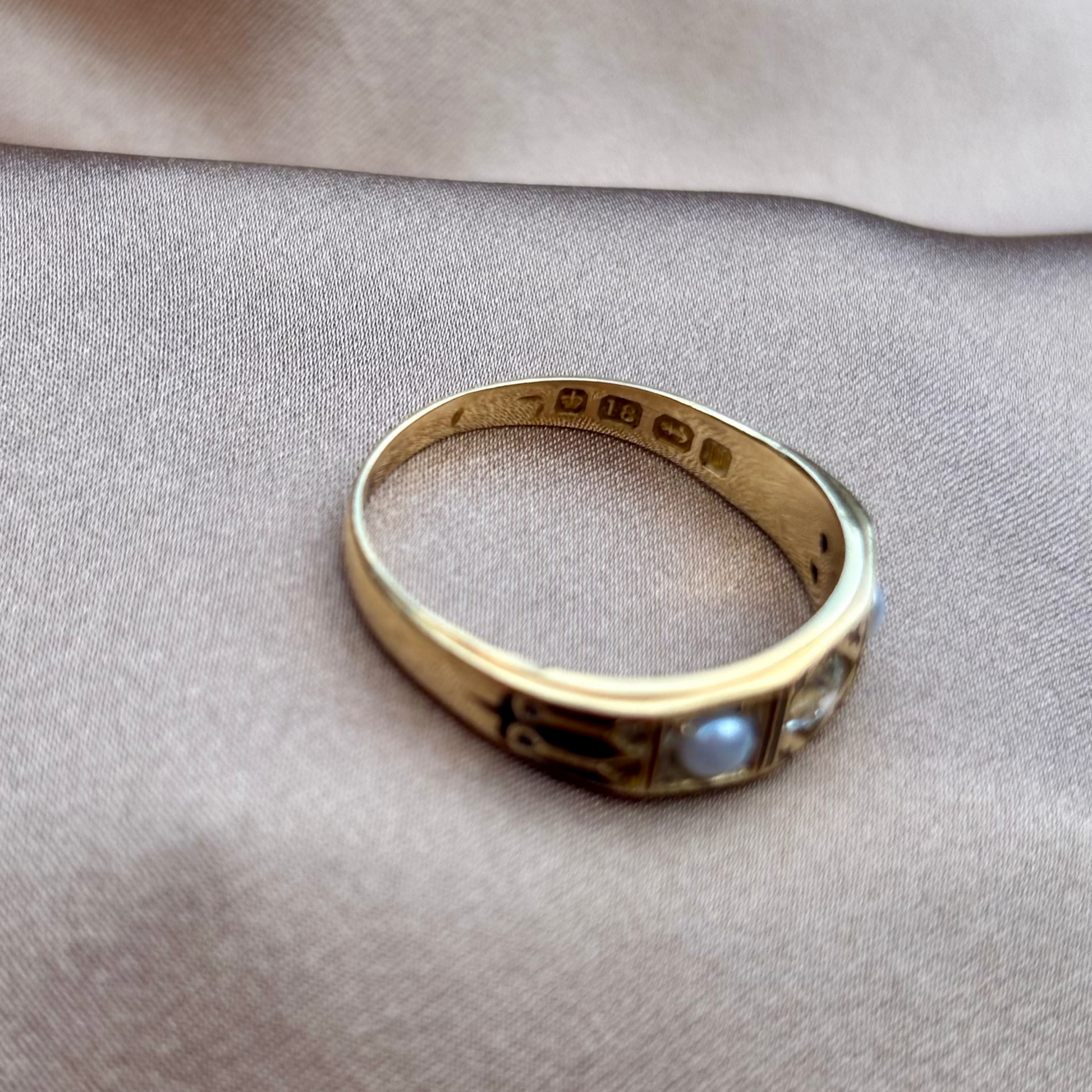 Gold ring with gemstones on a beige fabric background