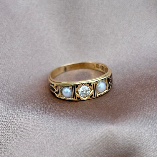 Gold mourning ring with embedded stones on a beige fabric background pearl and diamond