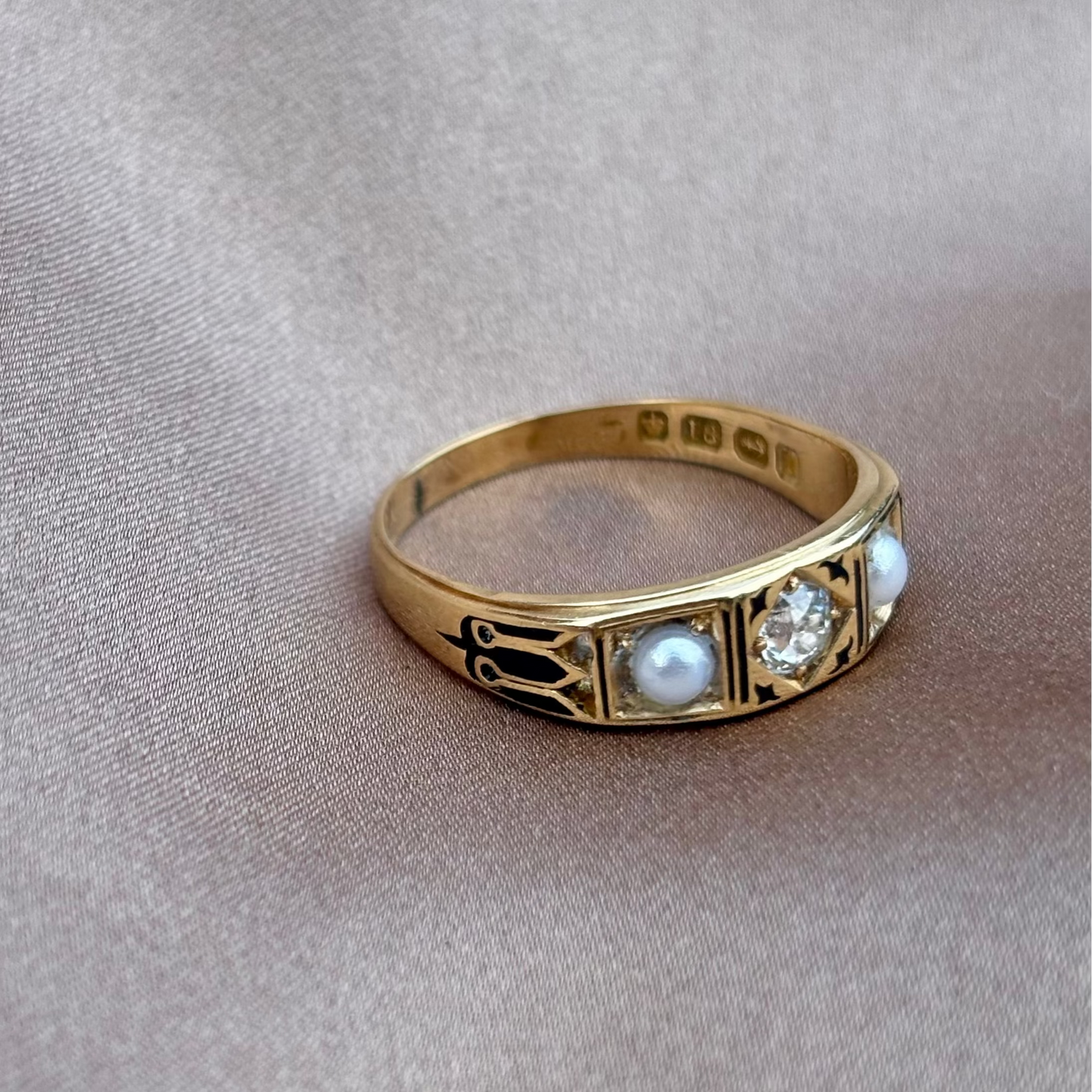 Gold ring with pearls and a diamond on a beige fabric background