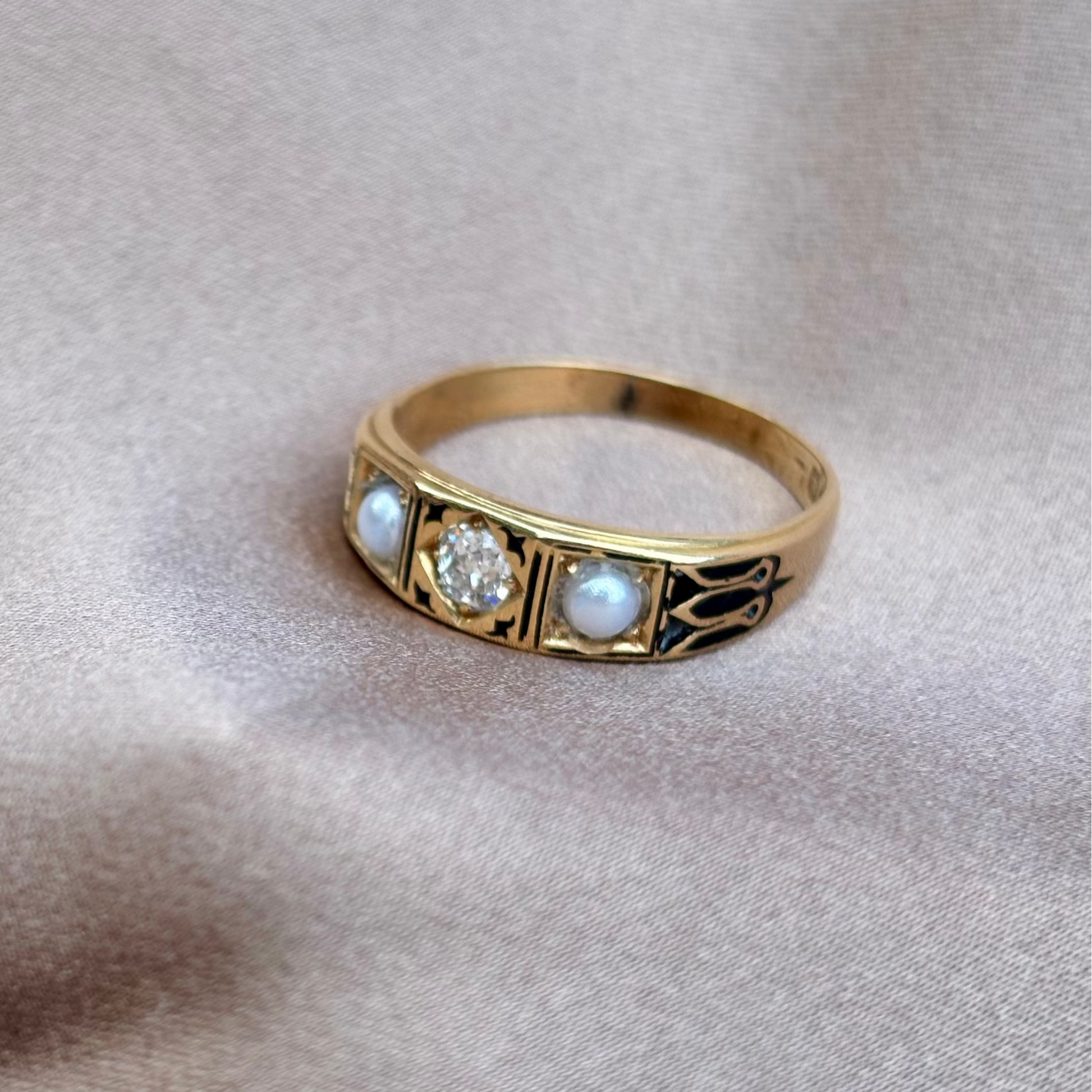 Gold ring with embedded stones on a beige fabric background
