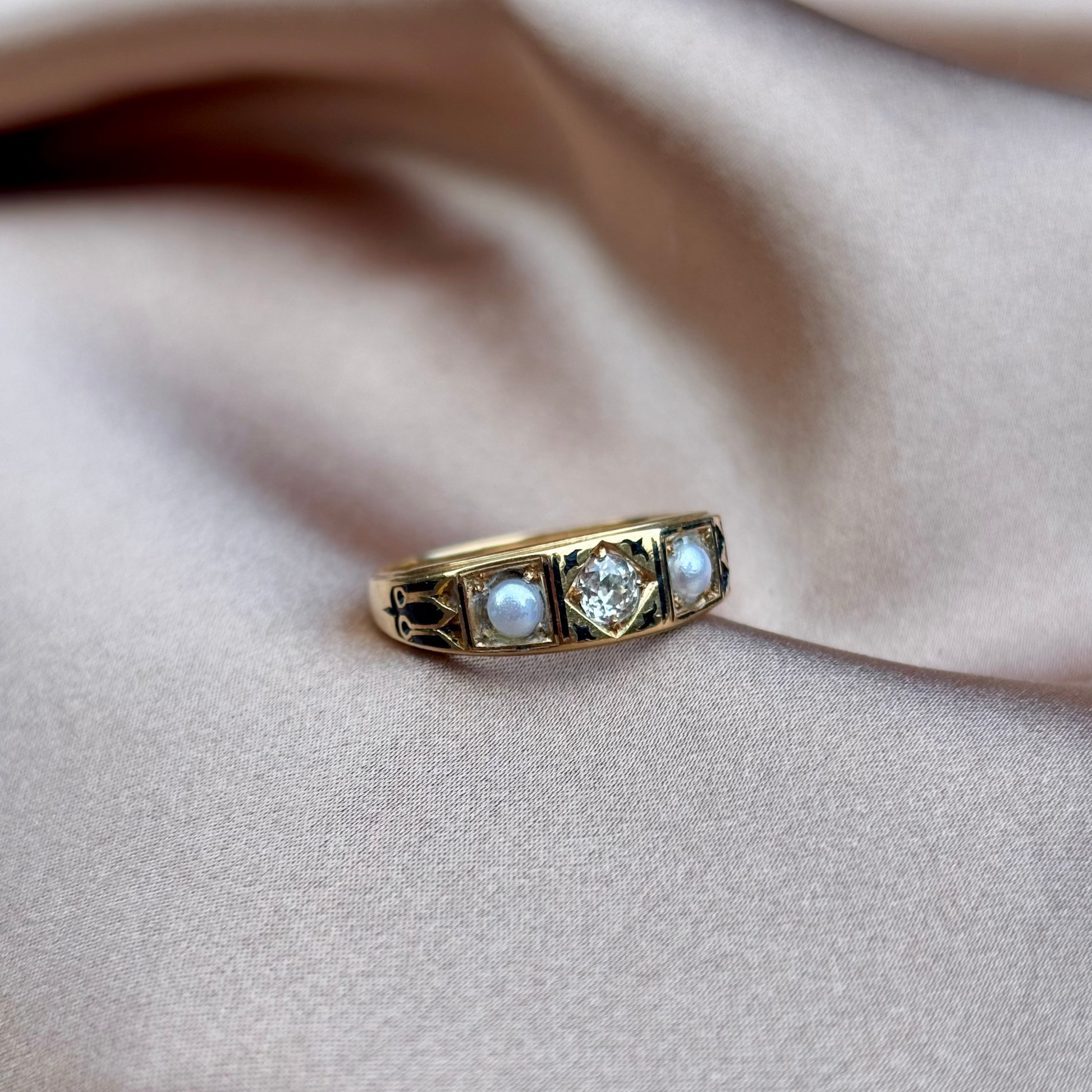 Gold ring with three gemstones on a beige fabric background