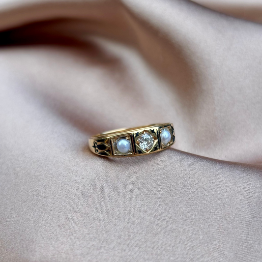 Gold ring with three gemstones on a beige fabric background