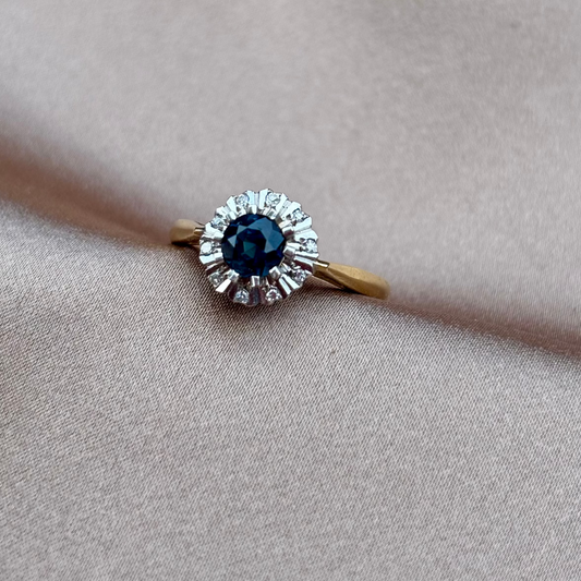 Gold ring with a blue gemstone on a beige fabric background