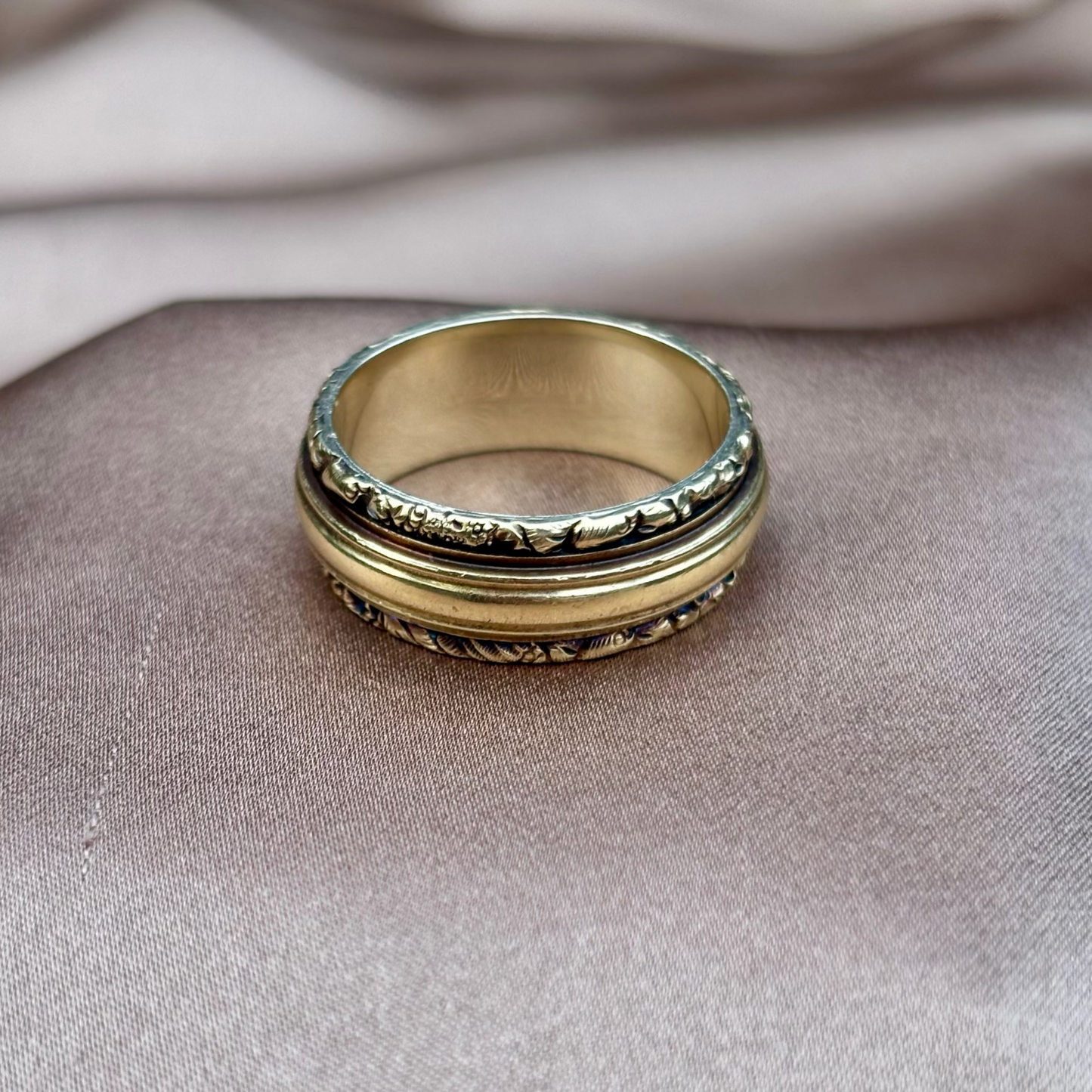 Gold ring with intricate design on a textured surface