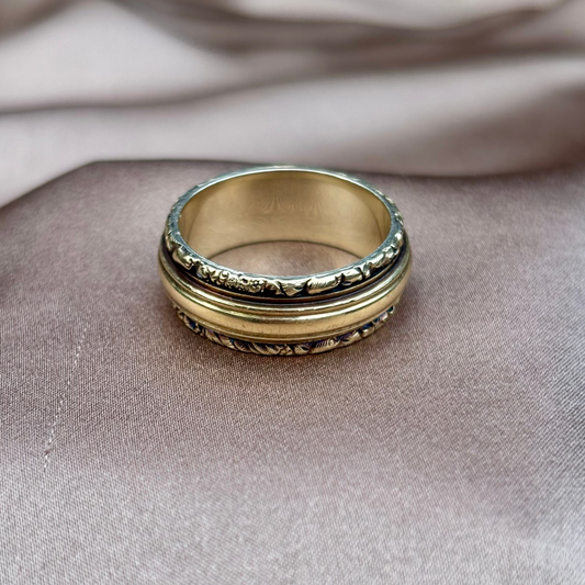 Gold ring with intricate design on a textured surface