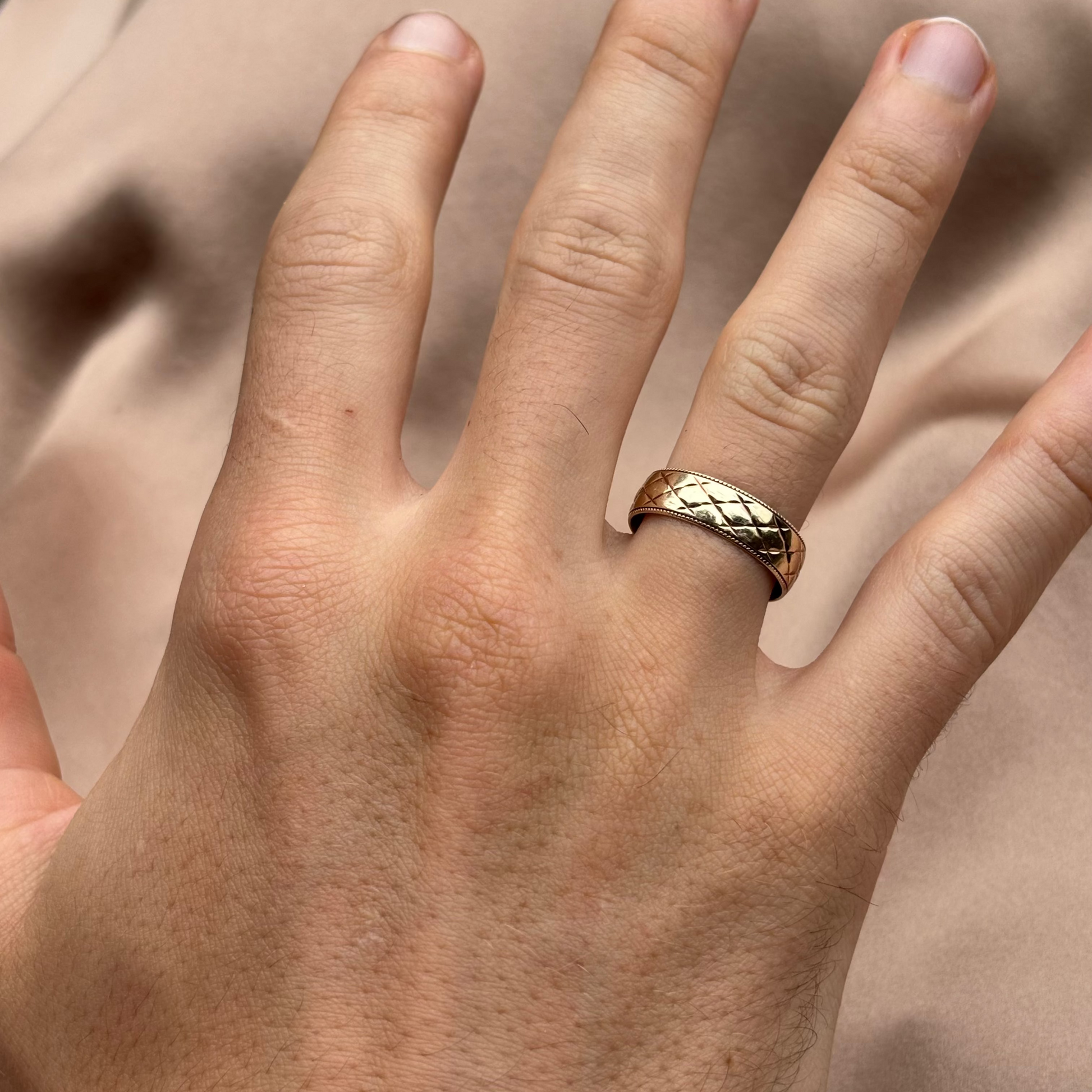 Hand wearing a gold ring with a blurred background