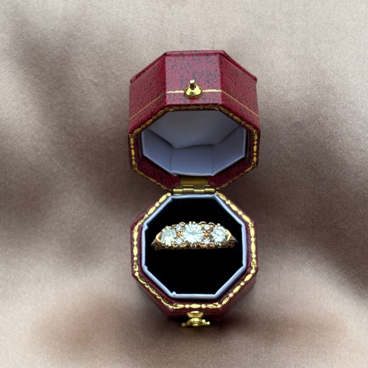 Open jewelry box with a diamond ring on a beige fabric background