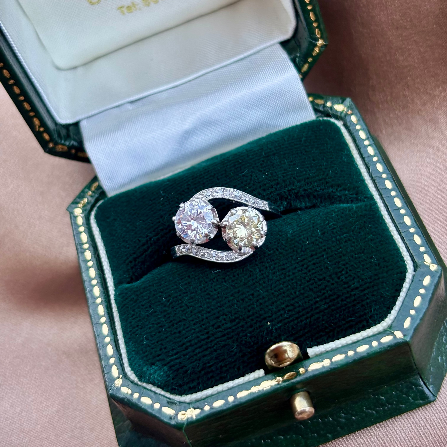 toi et moi crossover platinum Diamond ring on a beige fabric background