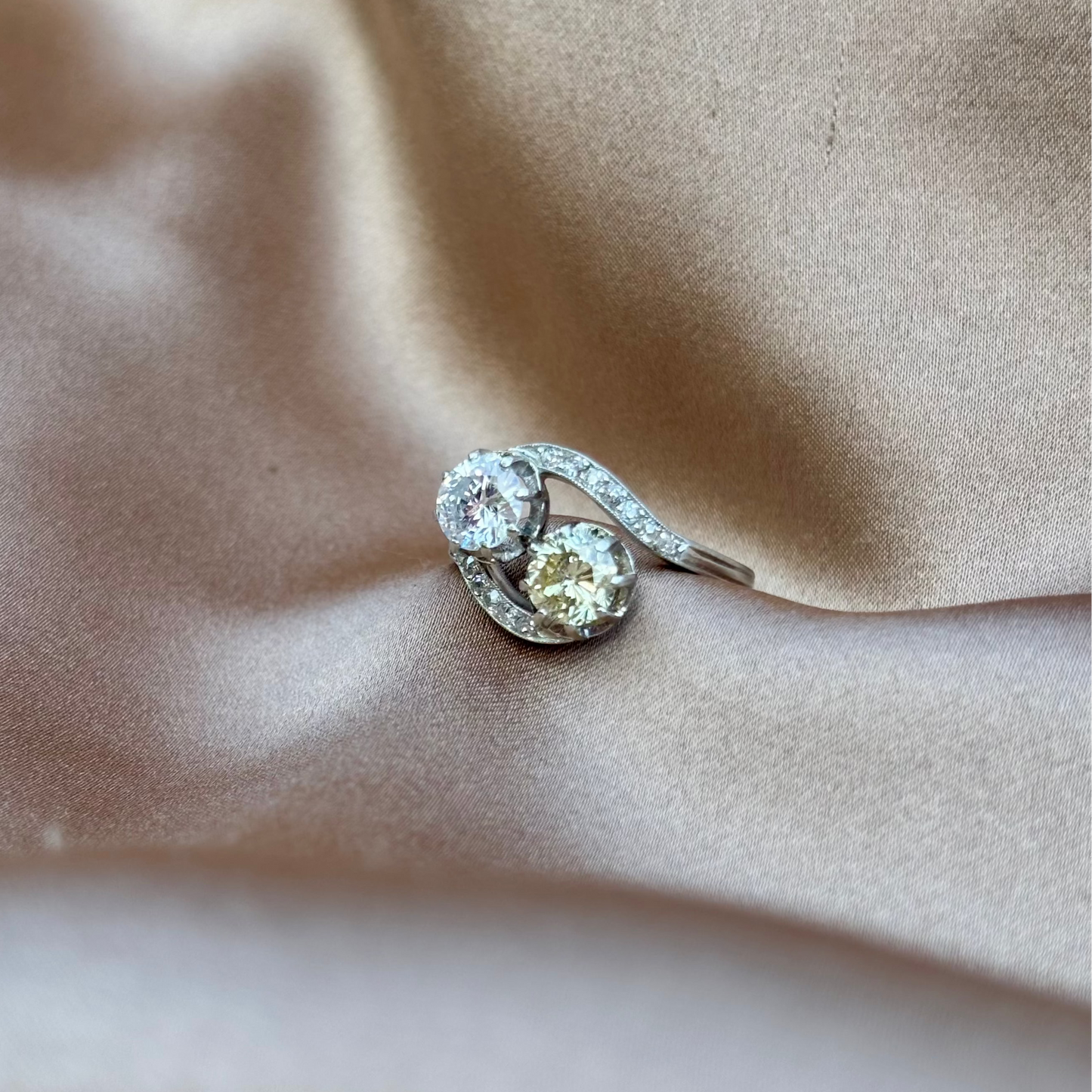 toi et moi crossover platinum Diamond ring on a beige fabric background