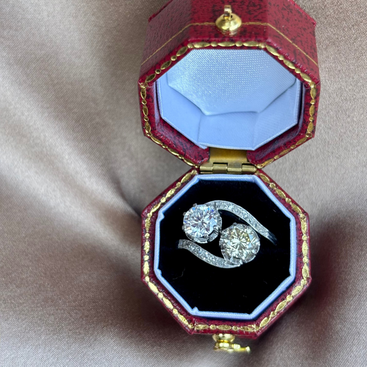 Diamond ring in a decorative red and gold box on a beige fabric background