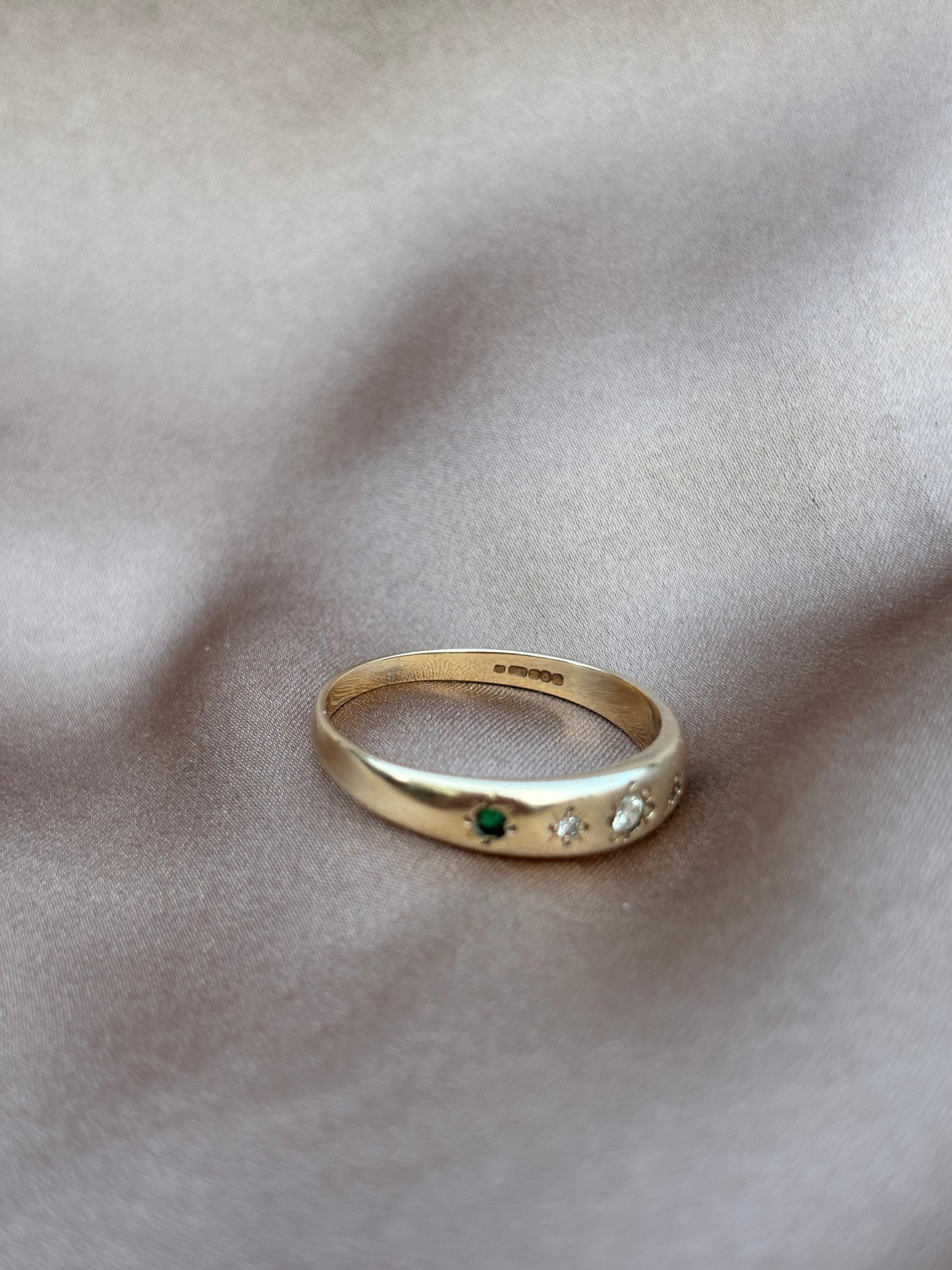 Gold ring with embedded gemstones on a soft fabric background