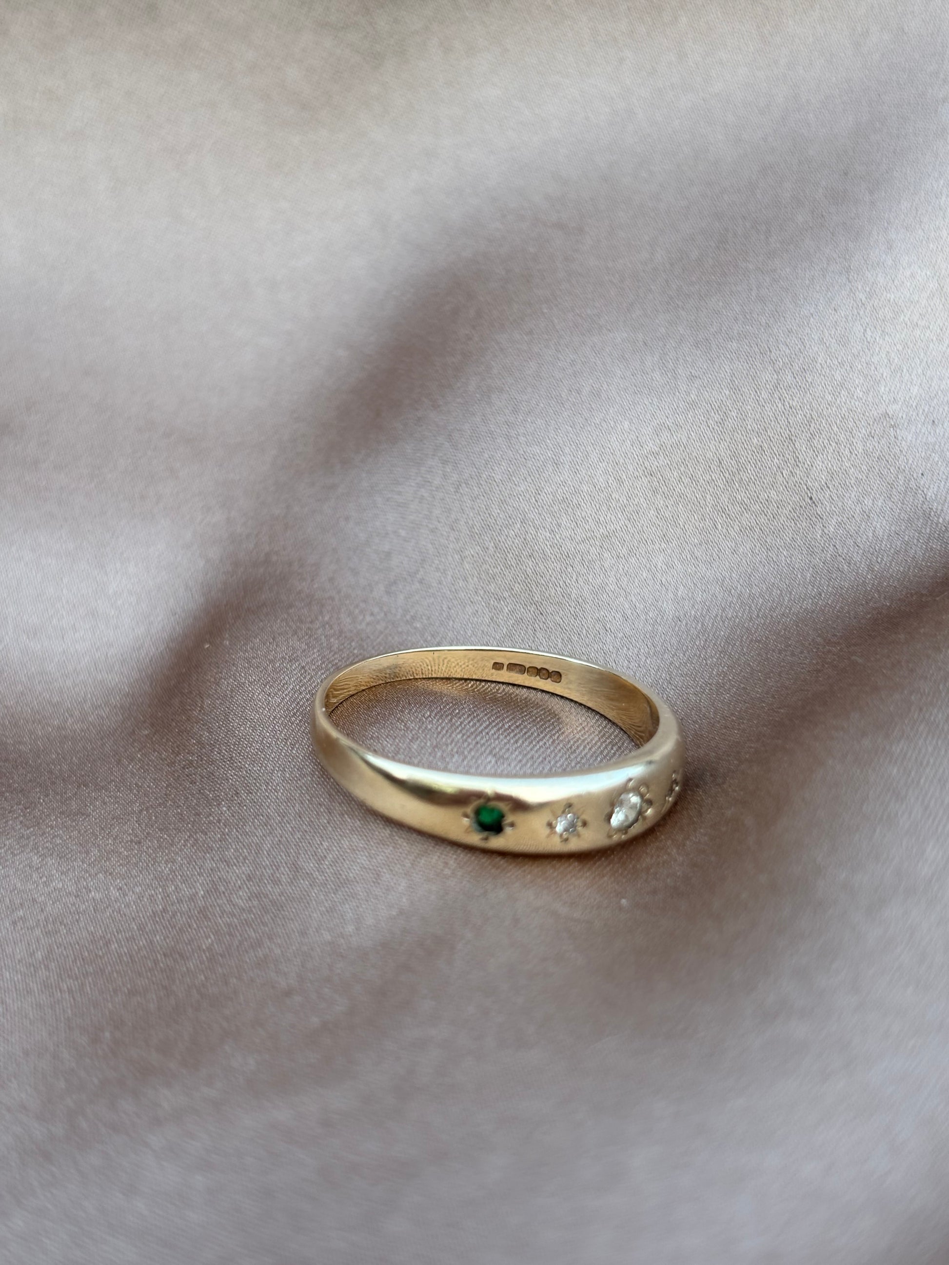 Gold ring with embedded gemstones on a soft fabric background