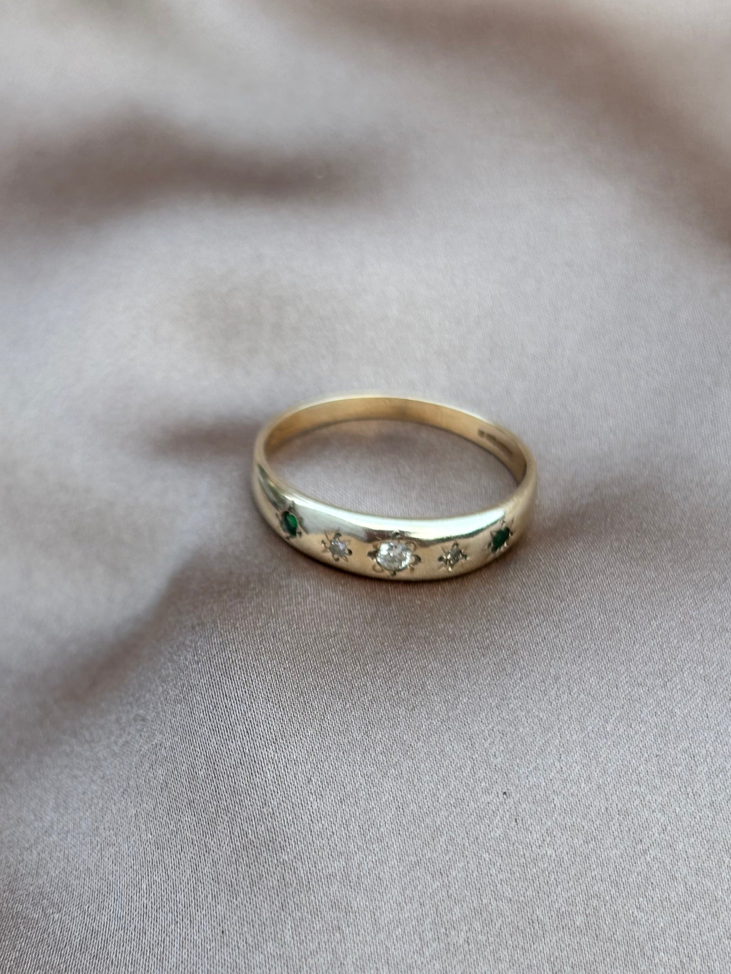 Gold ring with engraved details on a light gray fabric background